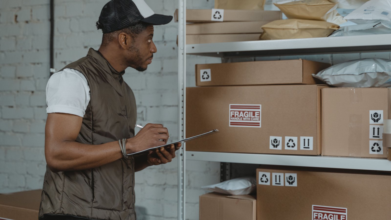 A worker with a clipboard checking labelled cartons on stockroom shelving