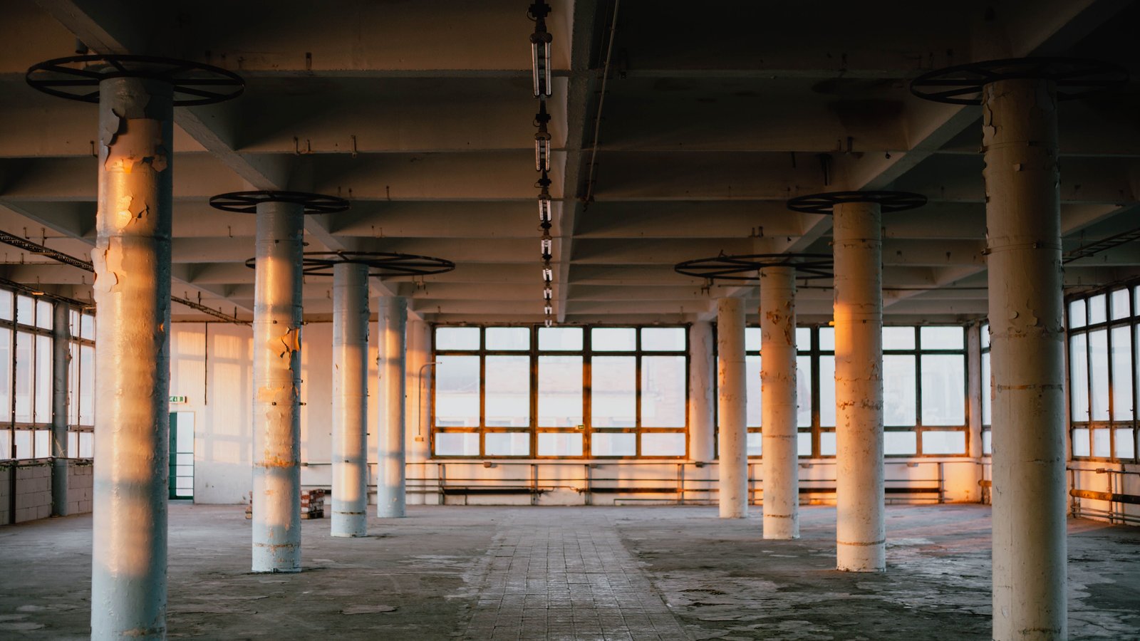 An empty industrial floor with columns and tall windows, ready to be set up