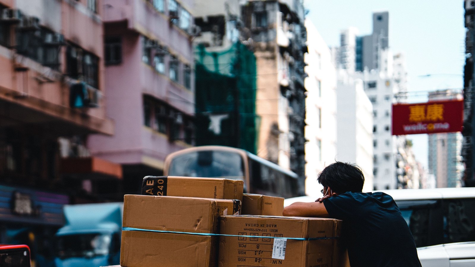 A pallet of strapped supplier cartons waiting at the kerb beside a city street